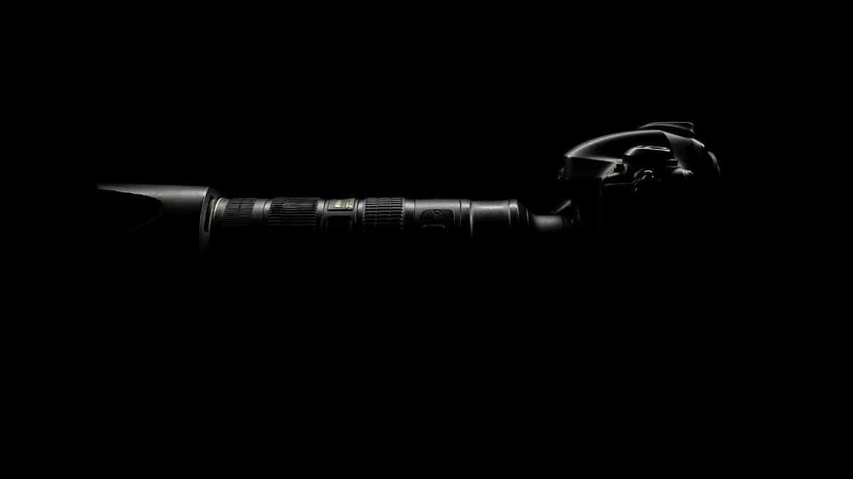 Artistic shot of a camera lens in darkness, emphasizing high-end photography equipment.