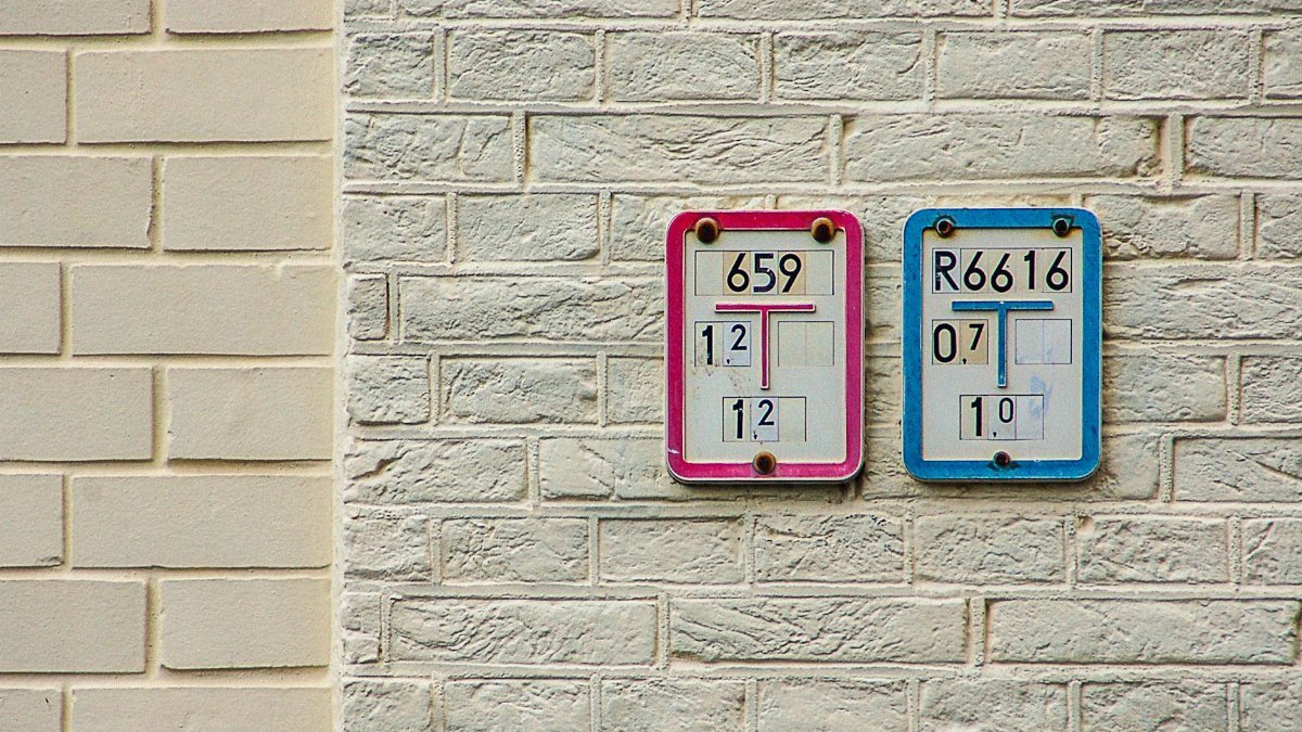 Close-up of numbered signs on a brick wall indicating water supply and intake details.