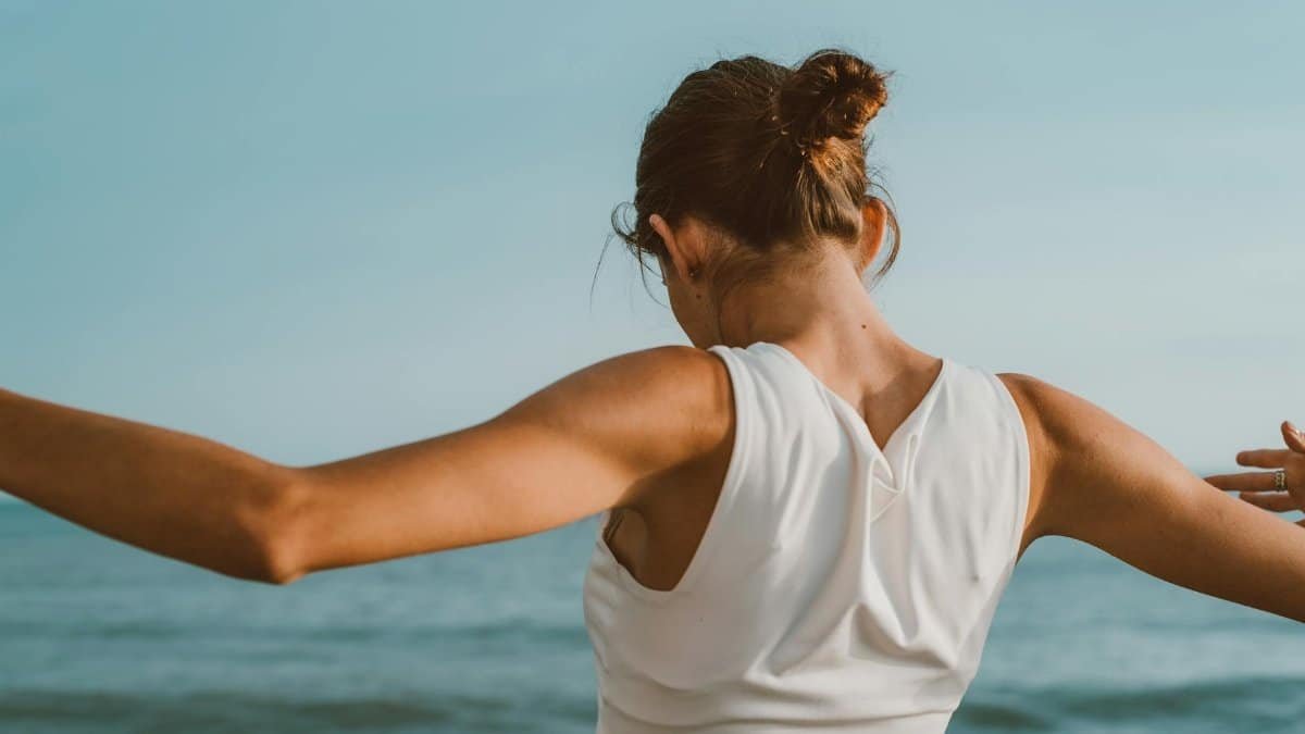Back view of a woman in athletic attire enjoying a serene moment by the ocean.