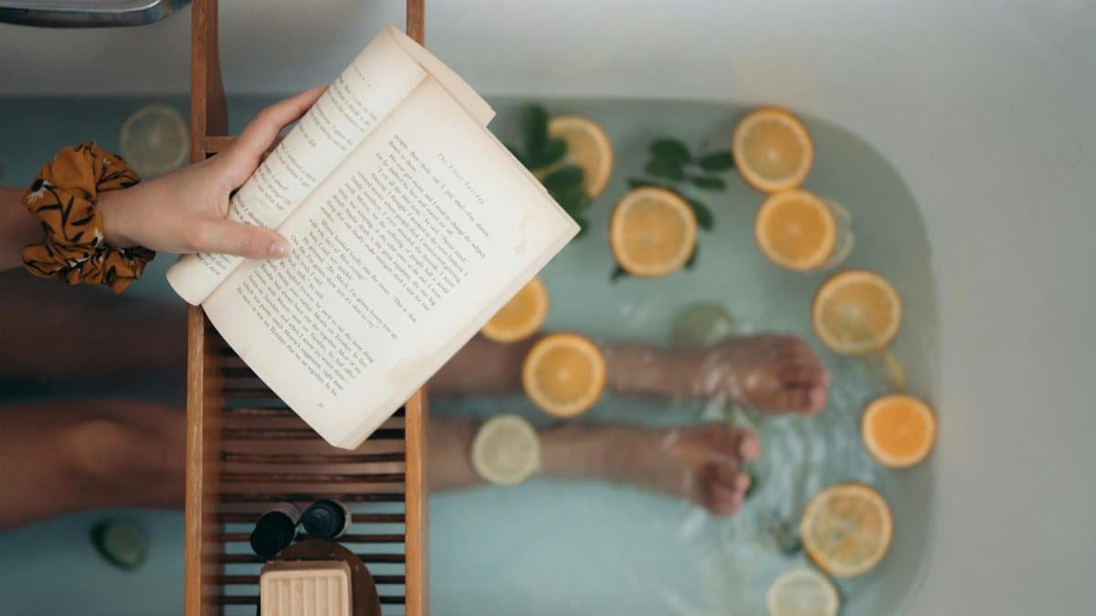 Person enjoying a citrus bath while reading a book, epitomizing relaxation.