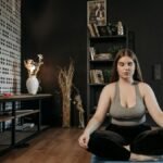 Woman in activewear meditating indoors, promoting wellness and mindfulness.