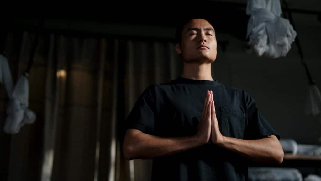 An adult male practicing meditation in a yoga studio, focusing on mindfulness and wellbeing.