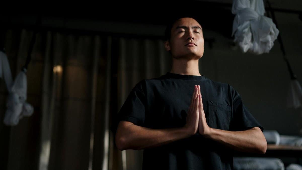An adult male practicing meditation in a yoga studio, focusing on mindfulness and wellbeing.