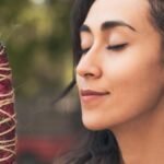 A serene woman enjoying the aroma of burning incense, promoting relaxation and mindfulness.