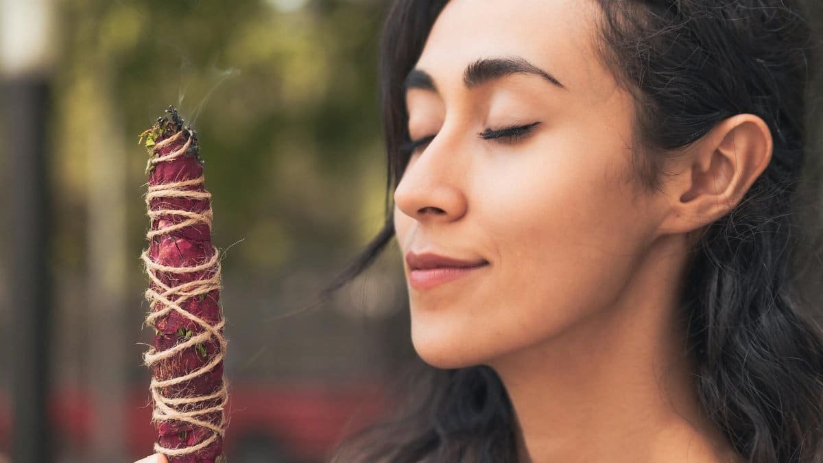 A serene woman enjoying the aroma of burning incense, promoting relaxation and mindfulness.