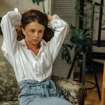 Woman sitting on a floral couch, appearing deep in thought in a cozy living room setting.