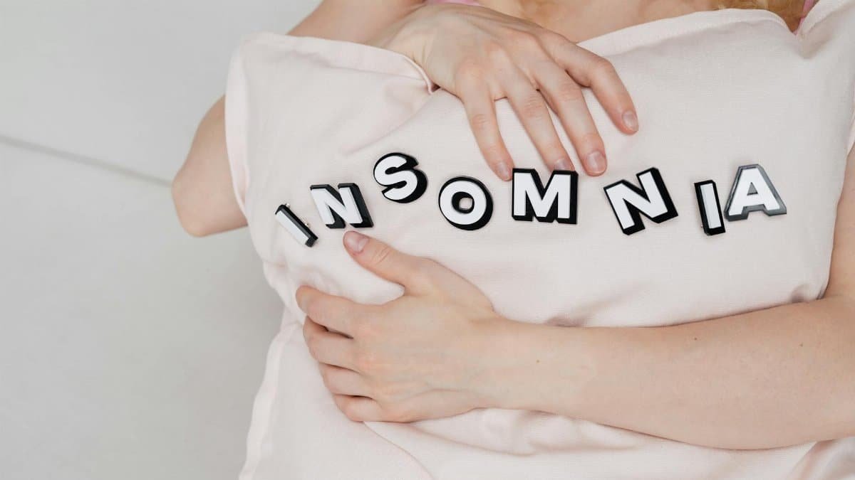 Close-up of a woman holding a pillow with 'insomnia' text, depicting sleep disorder.