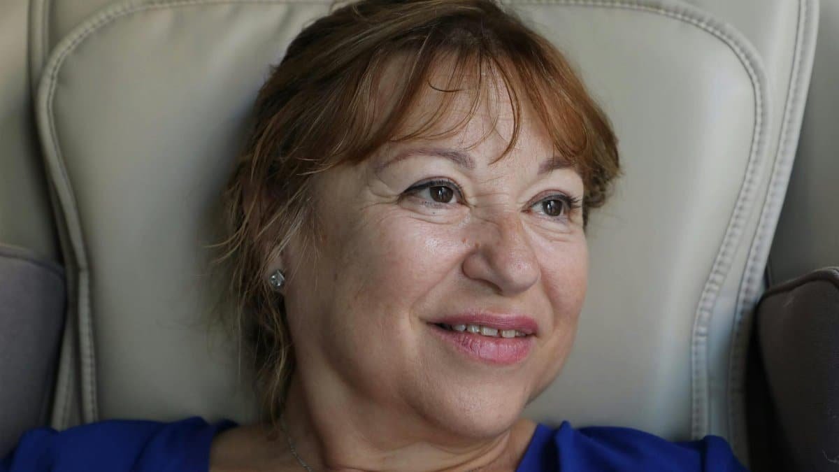 A smiling older woman relaxing indoors, exuding warmth and contentment.