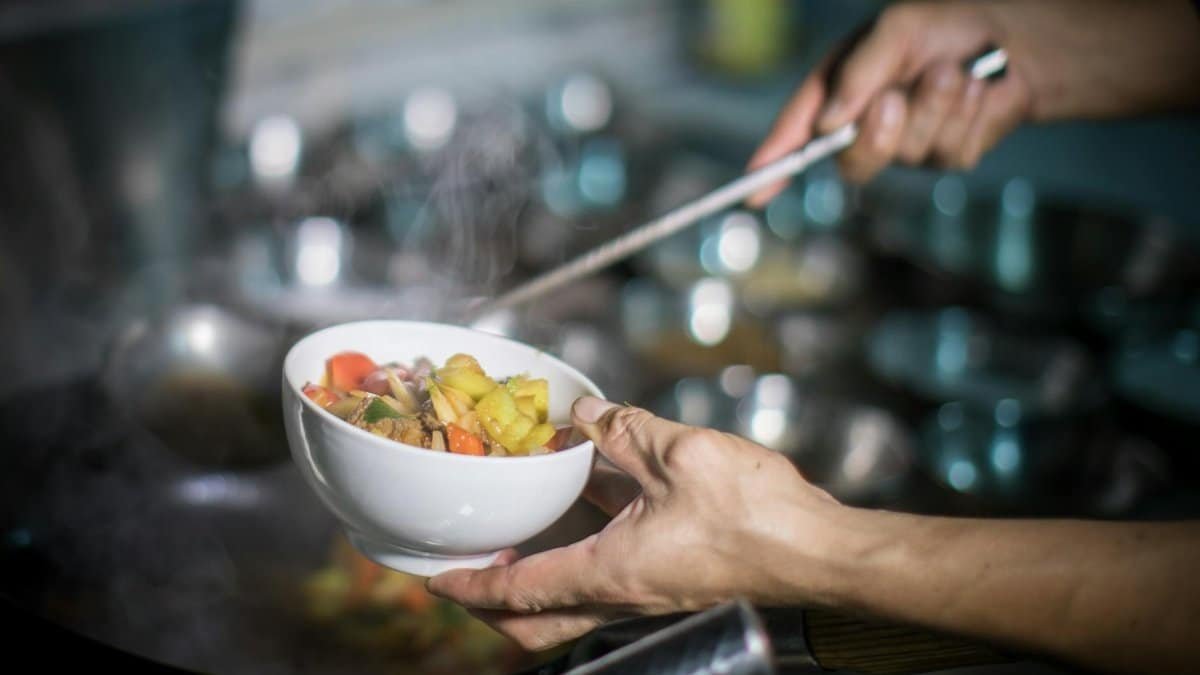 A chef skillfully prepares a fresh vegetable stir-fry in a bustling kitchen.