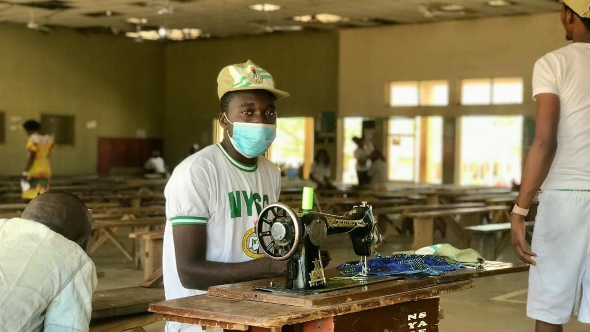 A young man sewing during the National Youth Service Corps program in Nigeria, promoting skill development.