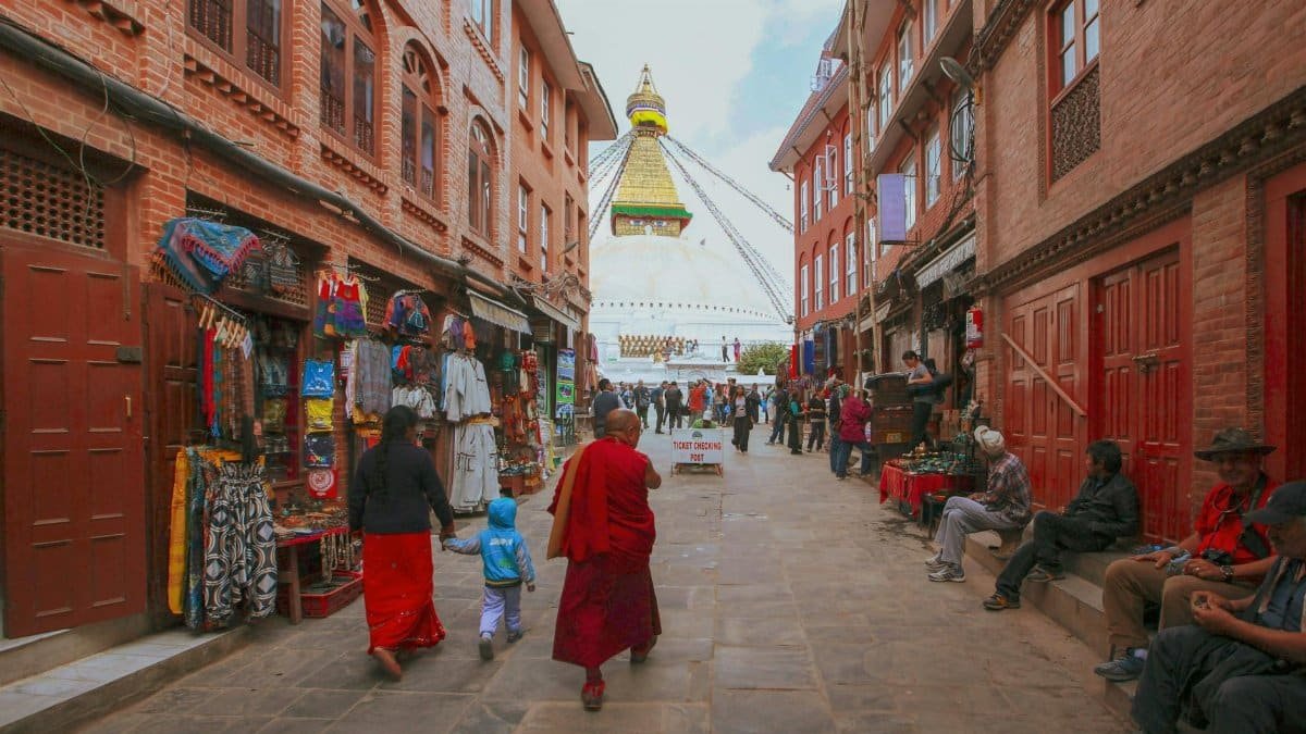 Monks and locals walk along a vibrant street near Boudhanath Stupa in Kathmandu, Nepal.