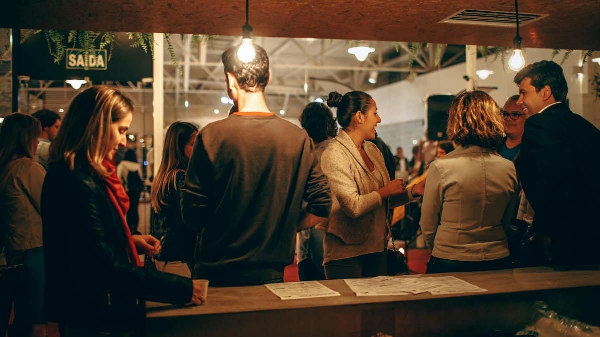 A lively indoor social gathering with people interacting warmly under cozy lighting.