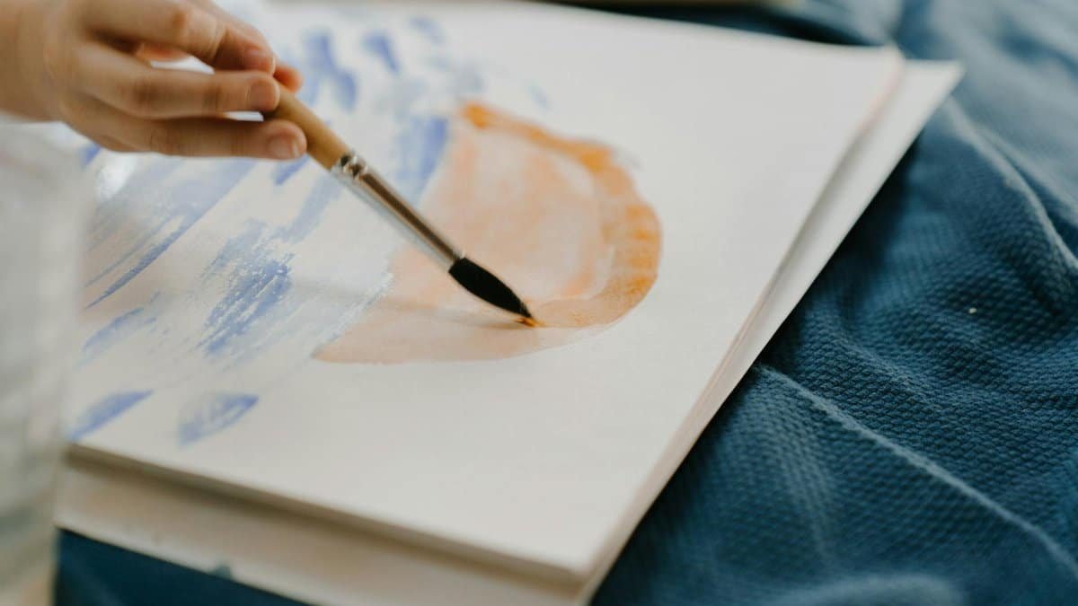 A close-up of a hand painting a creative abstract design with watercolor.