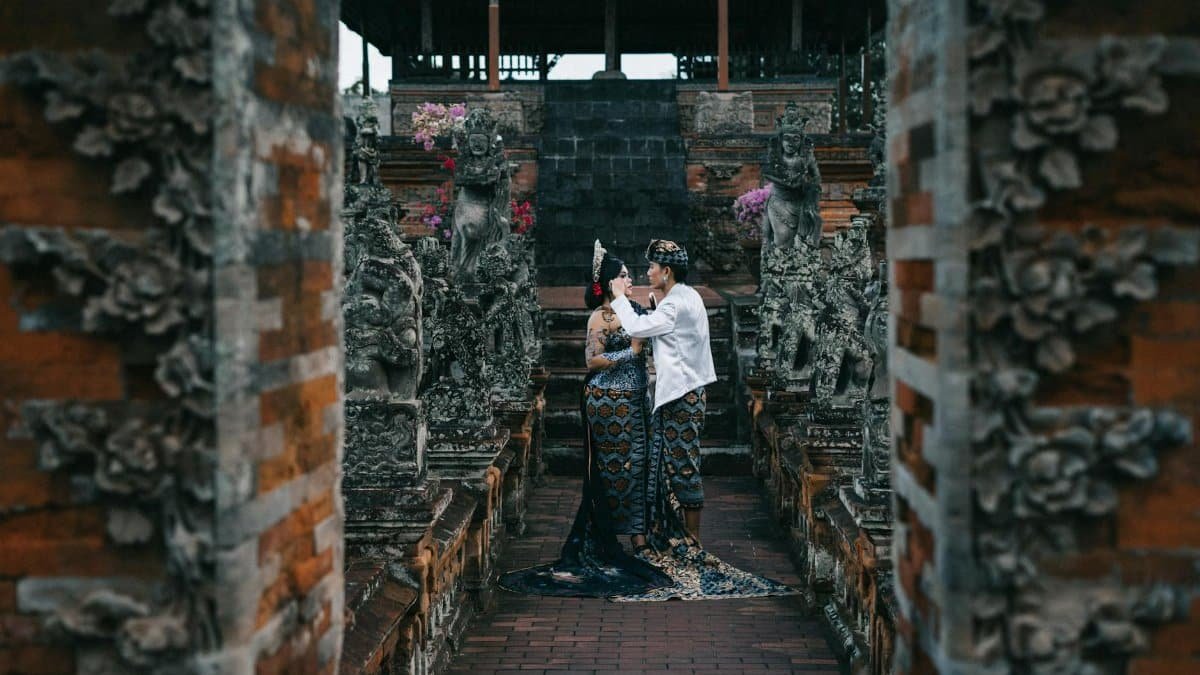 Asian couple in traditional wear at a temple, symbolizing cultural heritage and love.