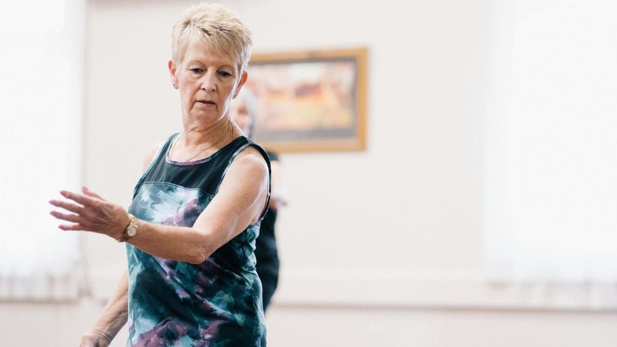 Elderly woman performing dance exercises indoors, focused and graceful.