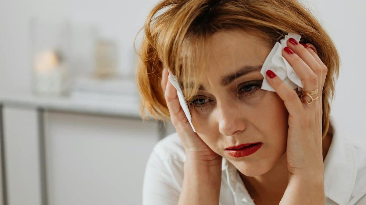 Close-up of a woman in distress holding tissues, expressing emotional sadness.