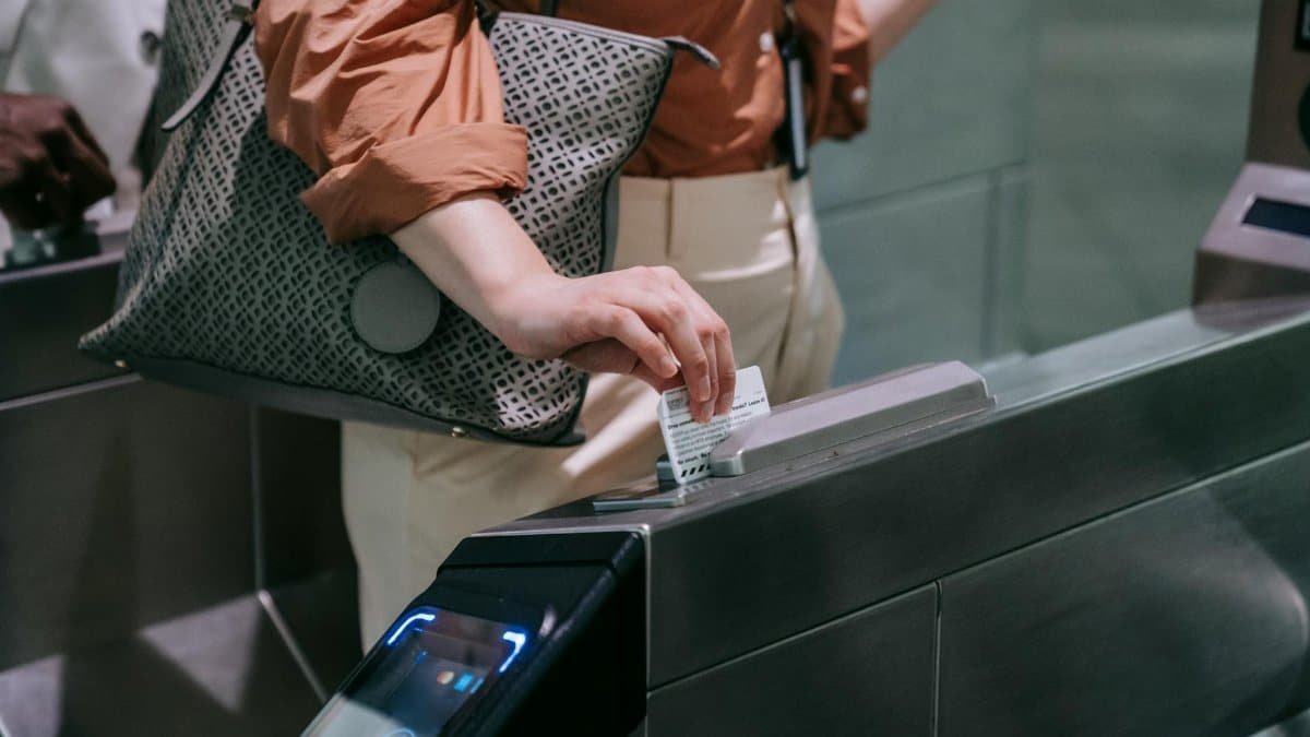 Close-up of woman using ticket at subway entrance turnstile, showcasing modern public transport system.