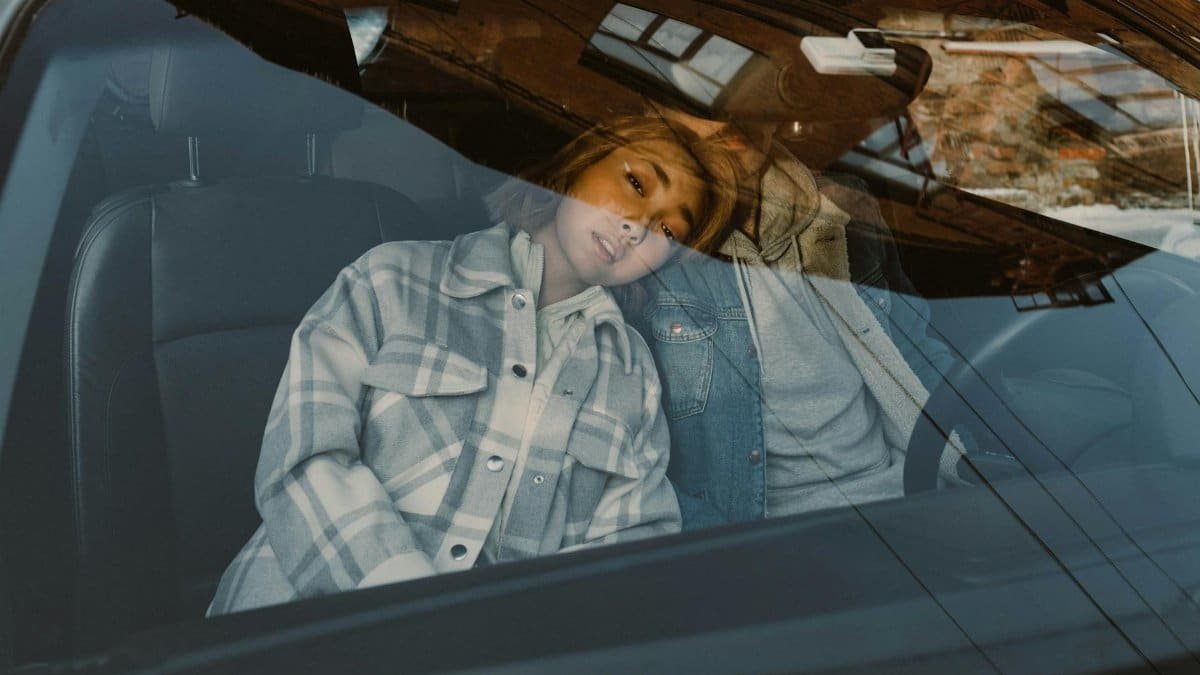 A couple relaxing inside a car, seen through the windshield, capturing a serene and intimate moment.