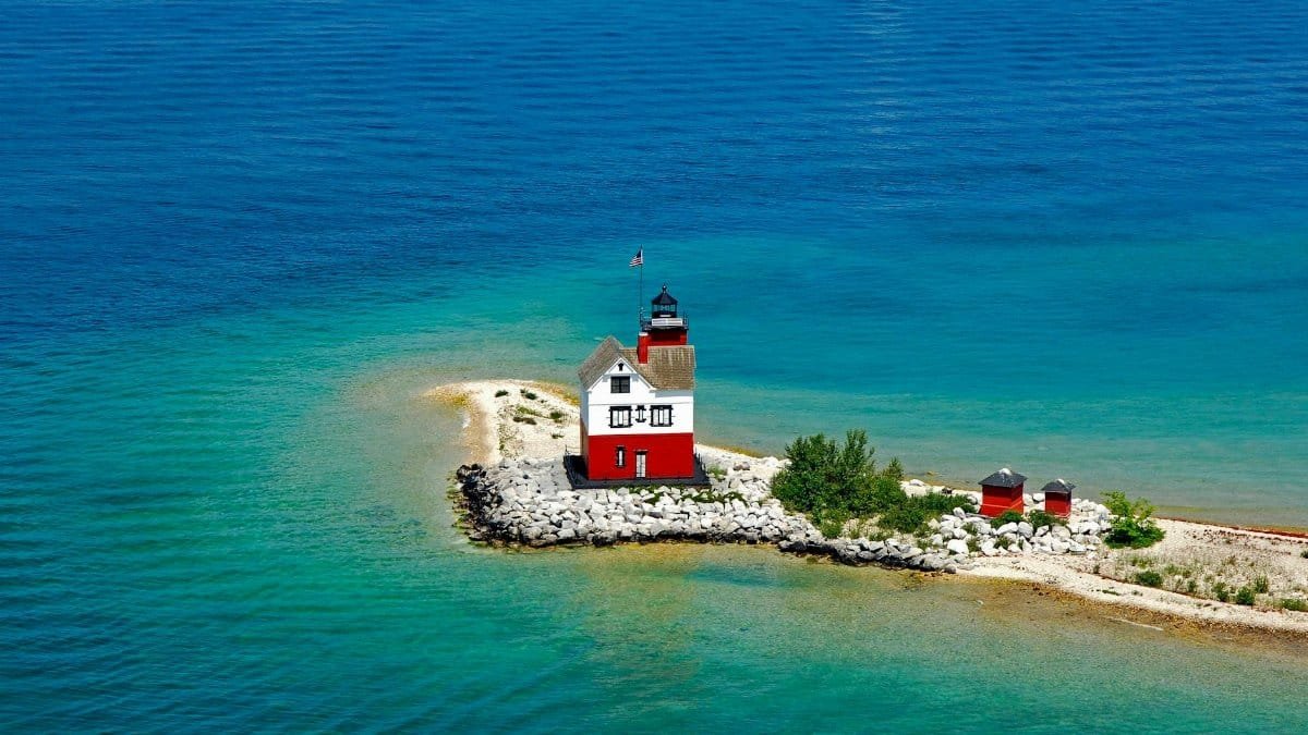 Aerial shot of Round Island Lighthouse on Mackinac Island surrounded by turquoise waters.