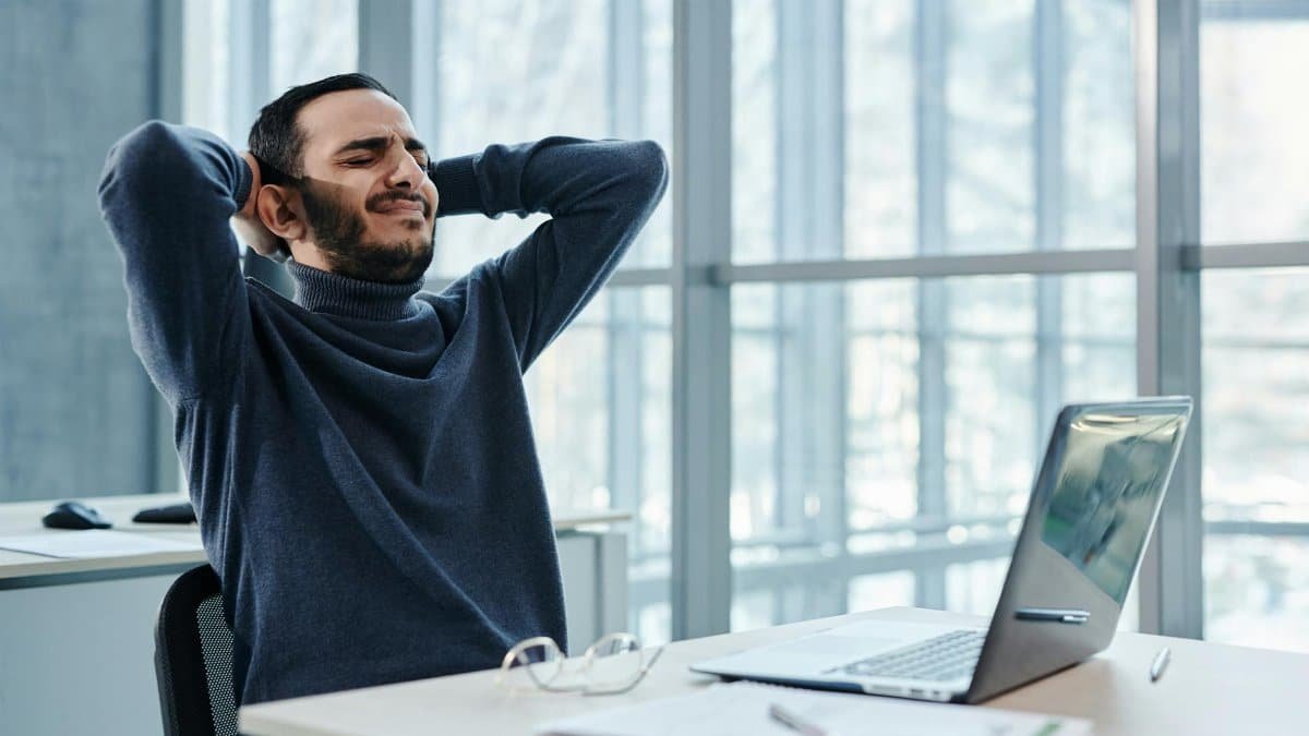 Man leaning back in office chair, appearing relaxed amidst a busy workday, reflecting stress management.