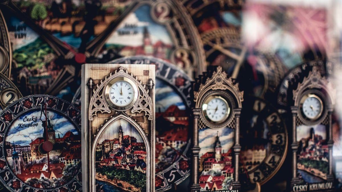 Detailed shot of ornate clocks featuring Český Krumlov landscapes, rich in design and decoration.