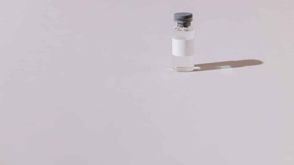A sterile vaccine vial isolated on a minimalist gray background, emphasizing health and medicine.