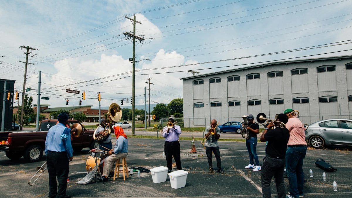 A lively street band performing with brass instruments in an urban parking lot.