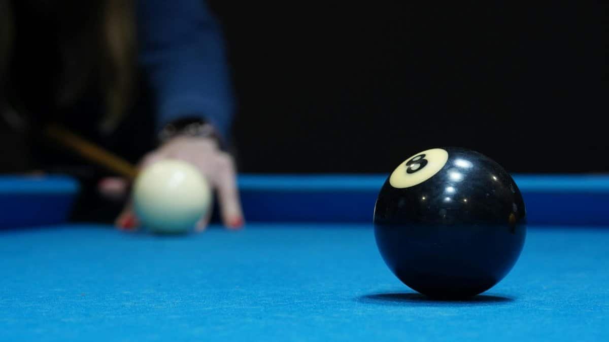 Focused view of the eight ball and cue ball on a blue pool table, ready for a shot.