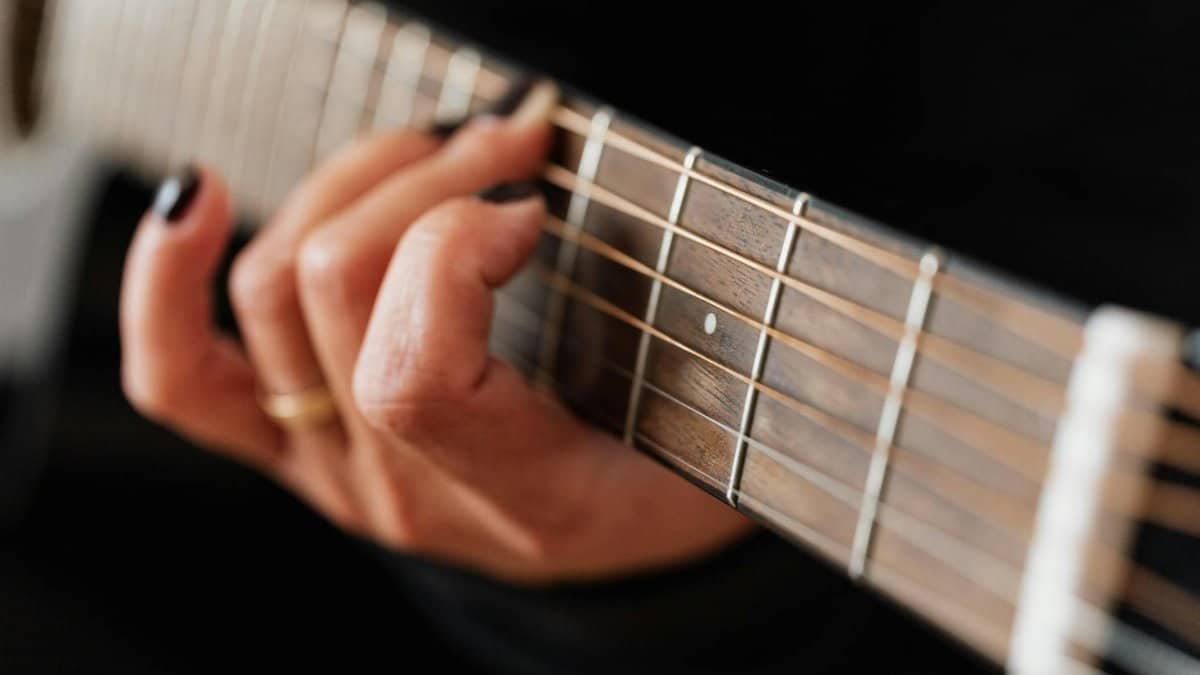 Detailed shot of a woman's fingers skillfully playing acoustic guitar strings, highlighting musical technique and passion.