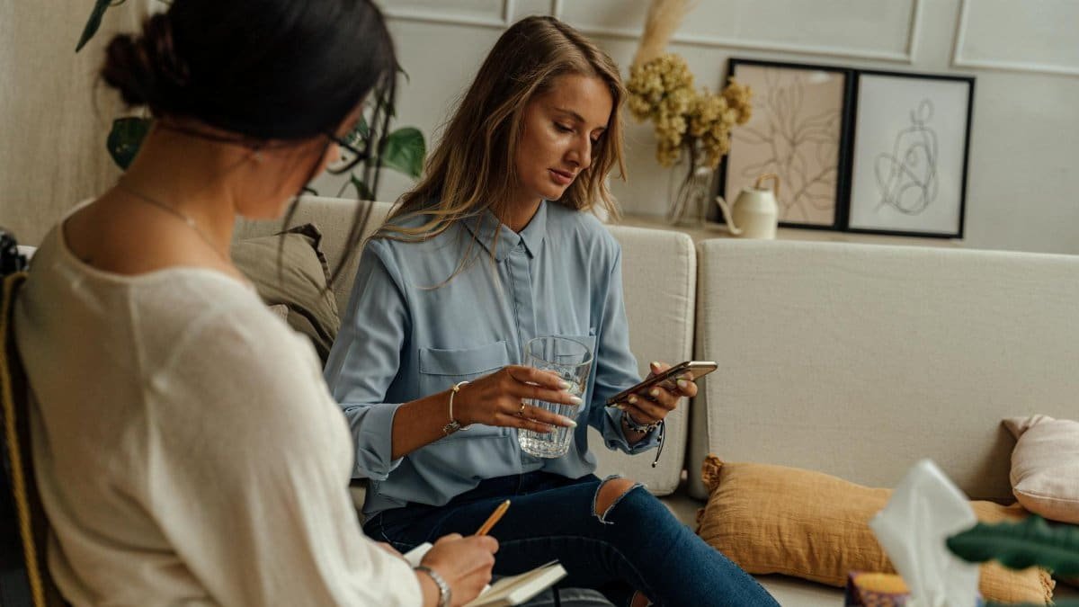 Two women engaged in a therapy session in a warm, stylish living room setting.