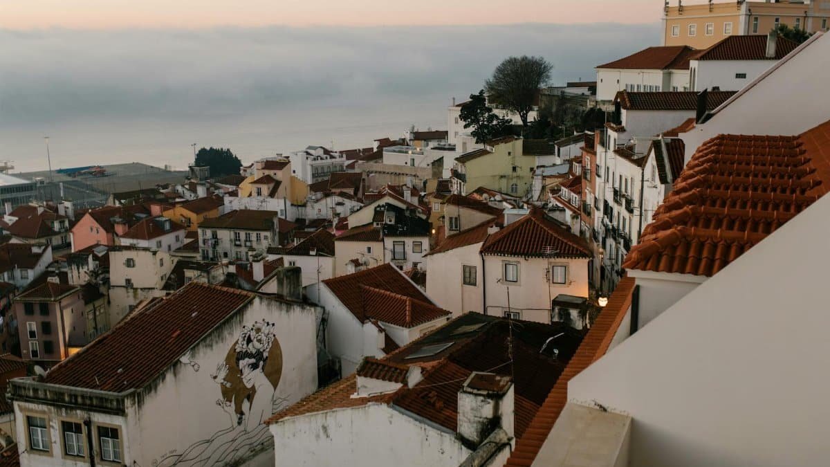 Small town with aged houses on hill against sea with clouds in sunset