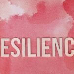 Word 'Resilience' on a pink watercolor background, symbolizing strength.