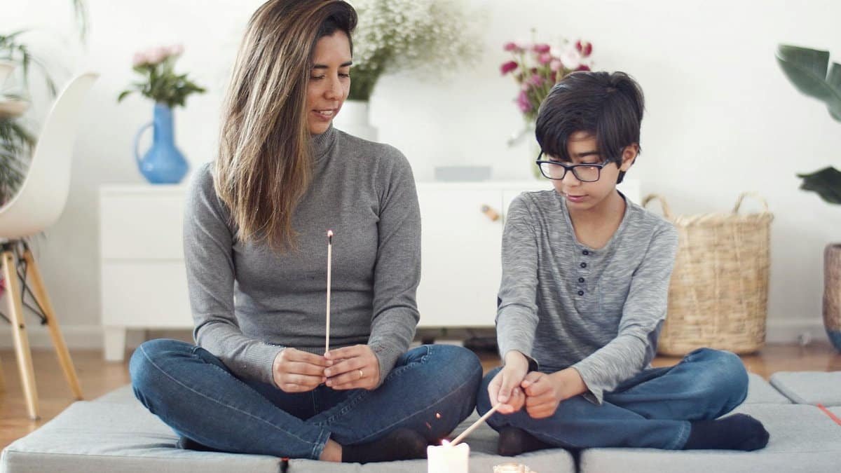 A mother and son practicing candle meditation at home. Relaxed and serene indoor setting.