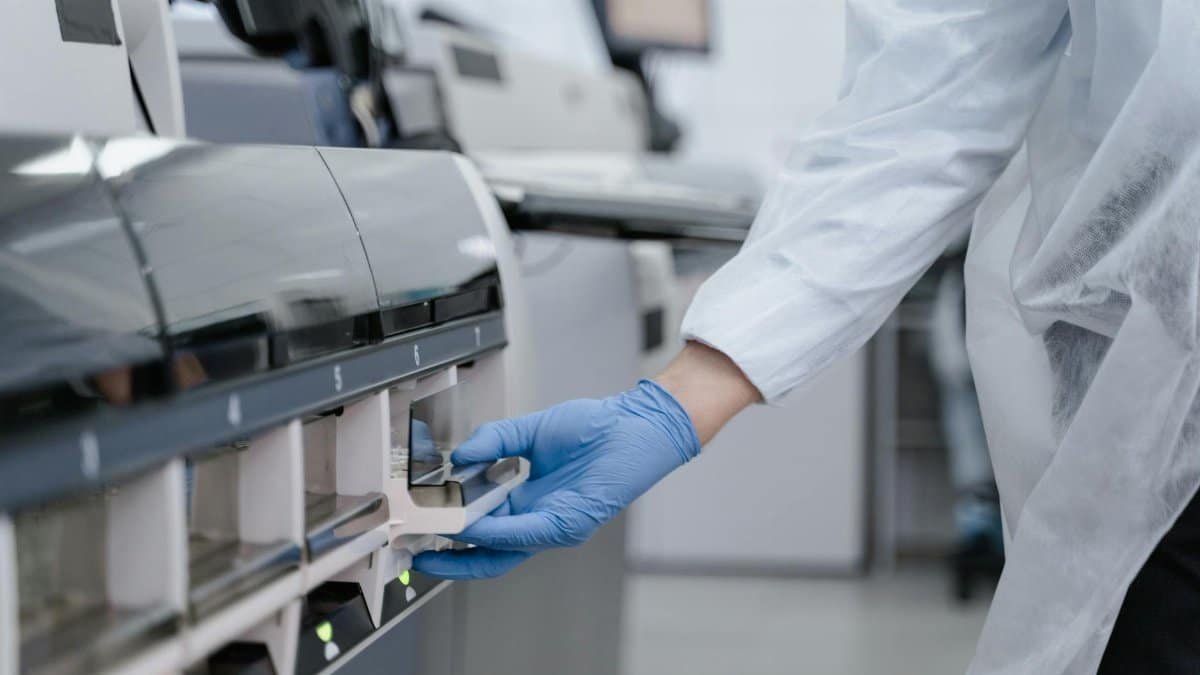 Lab technician in a white coat using equipment with precision in a sterile environment.