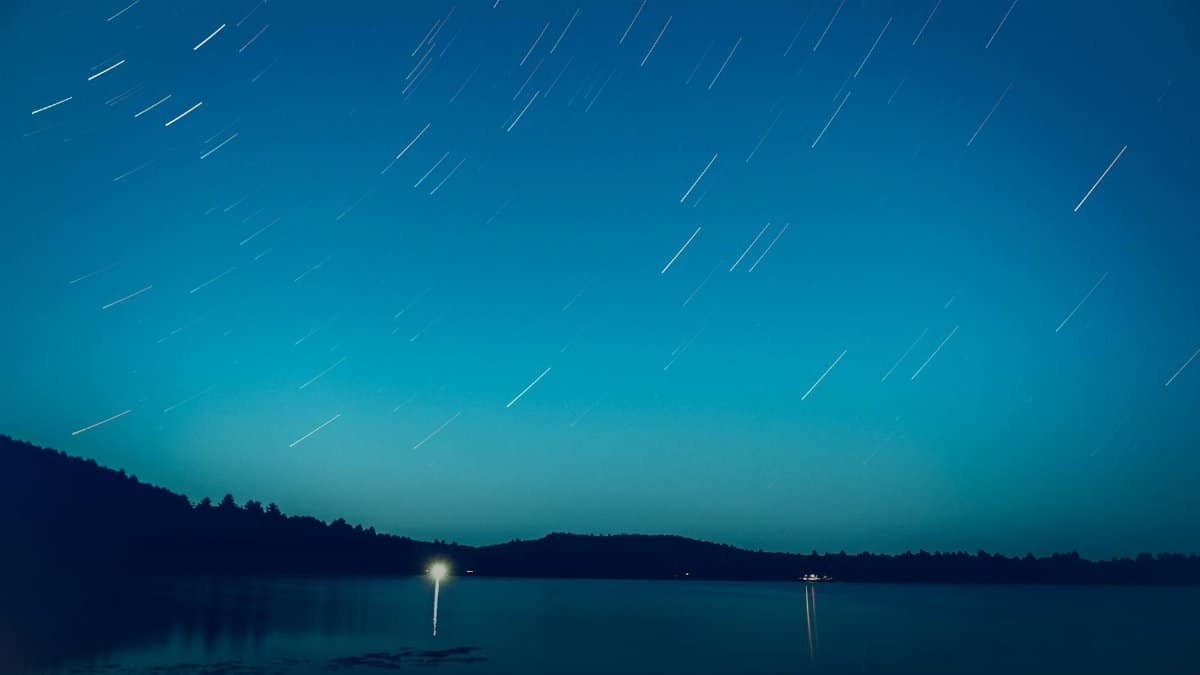 Long exposure of star trails over a lake in Barry's Bay, Canada, creating a serene night scene.