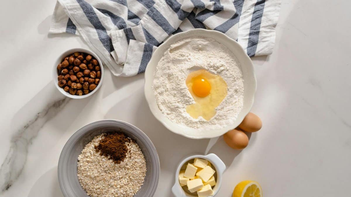 Top view of baking ingredients including flour, egg, and butter on a marble countertop.