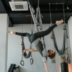 A person performs an aerial yoga pose gracefully in a modern studio setting.