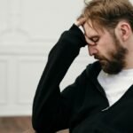 A man sits pensively with his hand on his face, capturing a moment of introspection and stress.