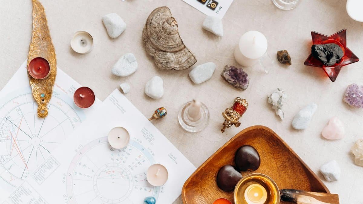 Flat lay of spiritual items including candles, crystals, and astrology charts for meditation.