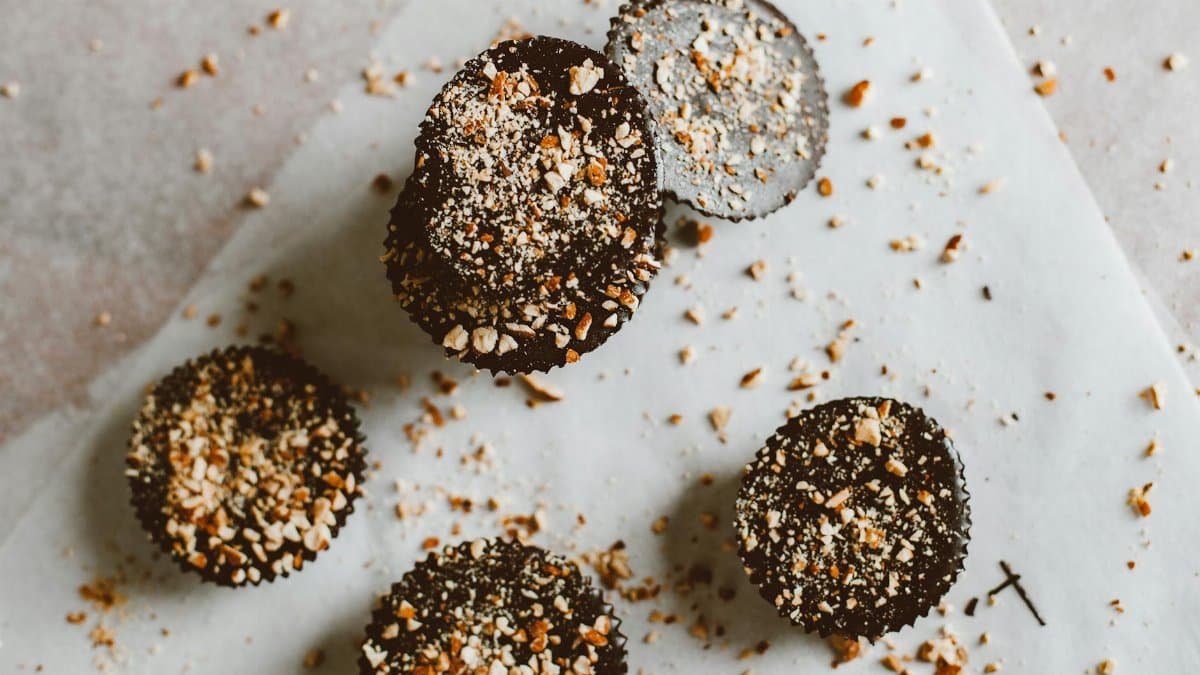 Top view of dark chocolate bites sprinkled with almonds on parchment paper.