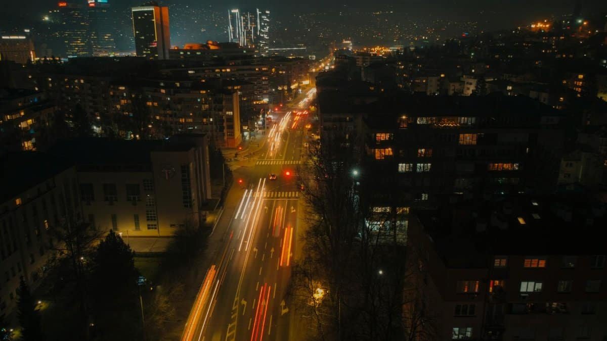 A dynamic view of a bustling city at night, showcasing colorful light trails and illuminated streets.