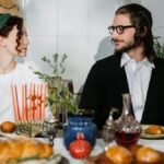 Couple enjoying a traditional Jewish meal with challah bread and menorah.