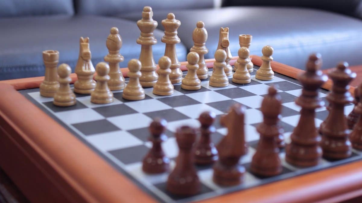 Close-up of a chess game on a wooden chessboard, showcasing strategic gameplay with carved pieces.