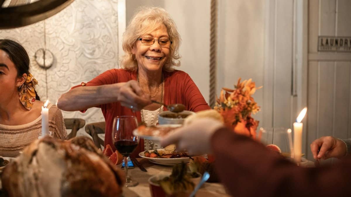 Senior woman enjoying a Thanksgiving dinner, sharing hearty meals with family indoors.