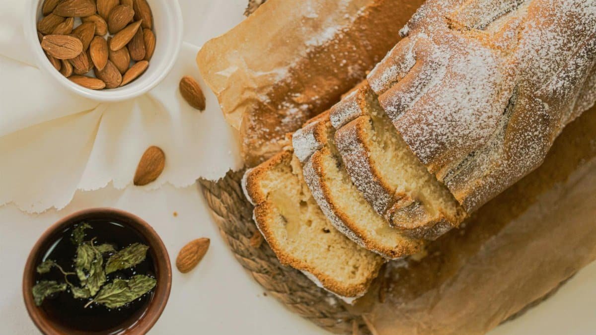 Close-up of freshly sliced homemade bread served with almonds and herbal tea.