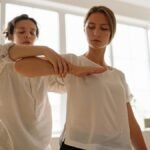 Two women participating in a therapy session indoors, focusing on relaxation and wellness.