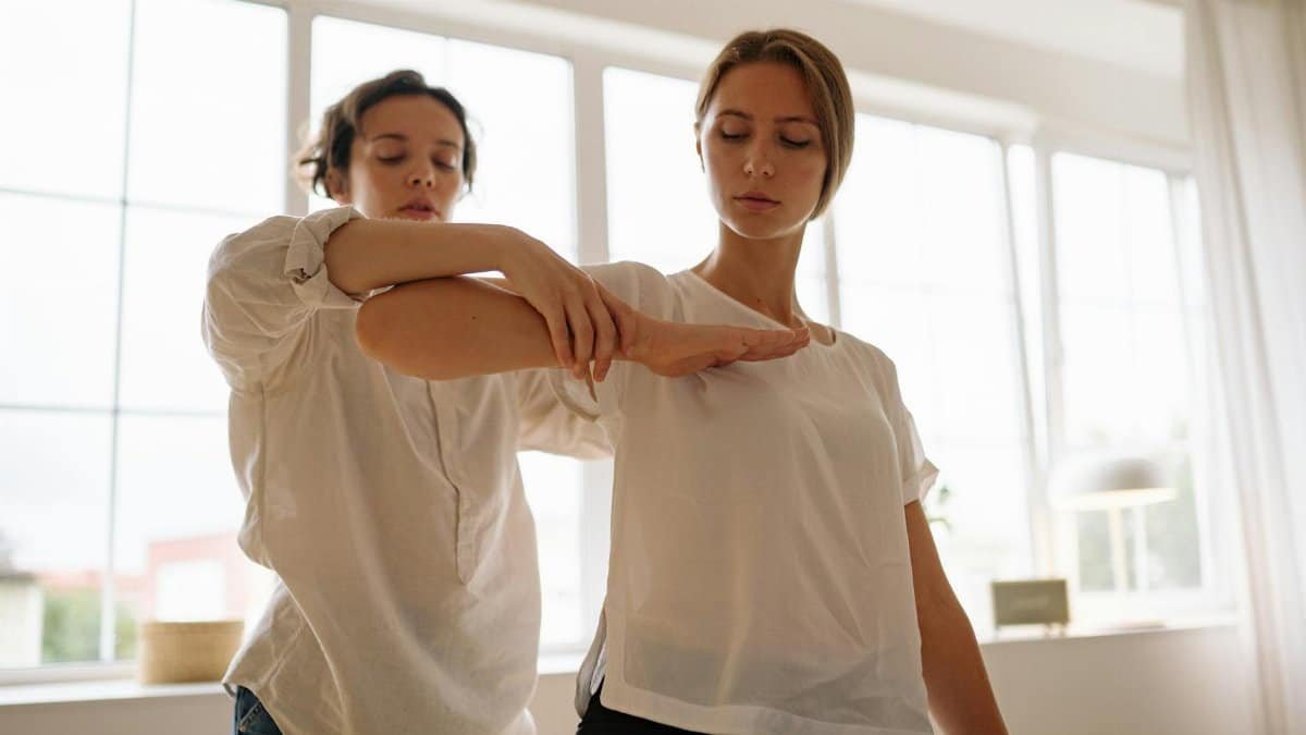 Two women participating in a therapy session indoors, focusing on relaxation and wellness.