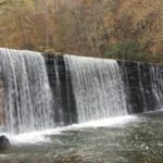 Beautiful waterfall cascading over a stone wall surrounded by fall foliage in Lynchburg, Virginia.