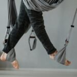 Feet suspended in aerial yoga in a modern, serene studio setting.