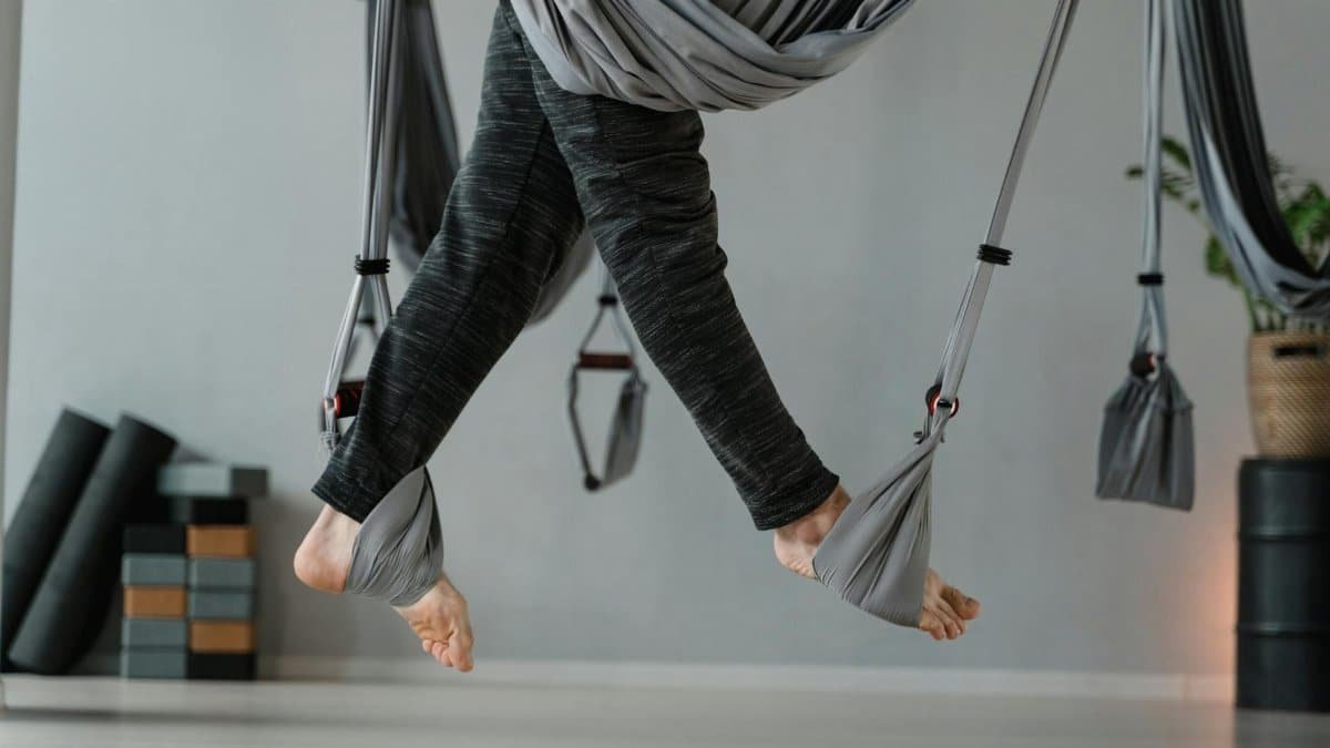 Feet suspended in aerial yoga in a modern, serene studio setting.